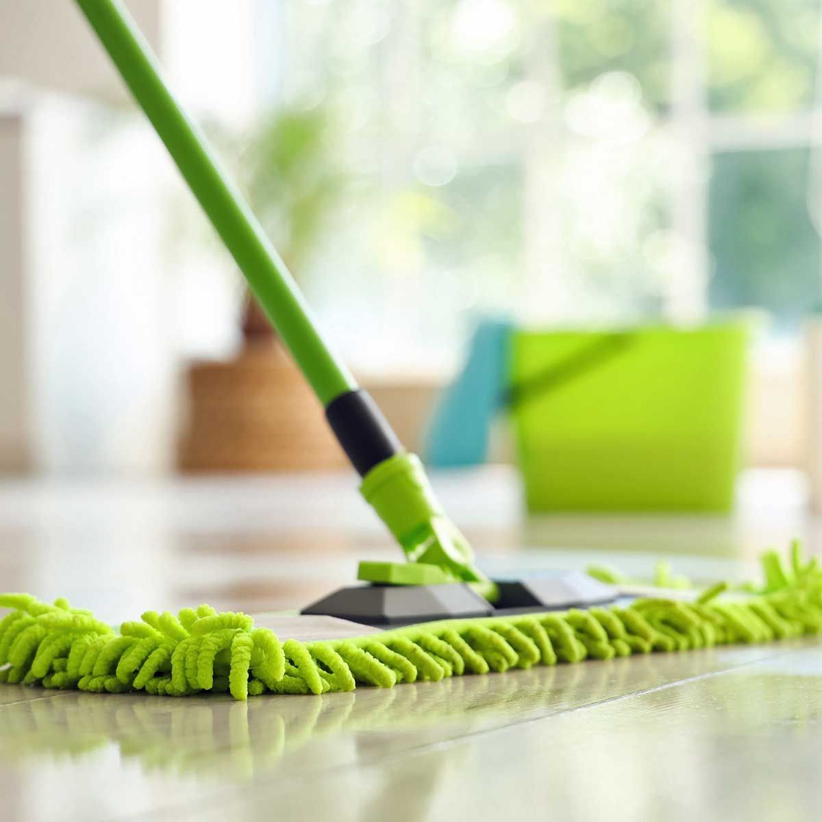 Green mop cleaning a shiny floor; green bucket in the background.