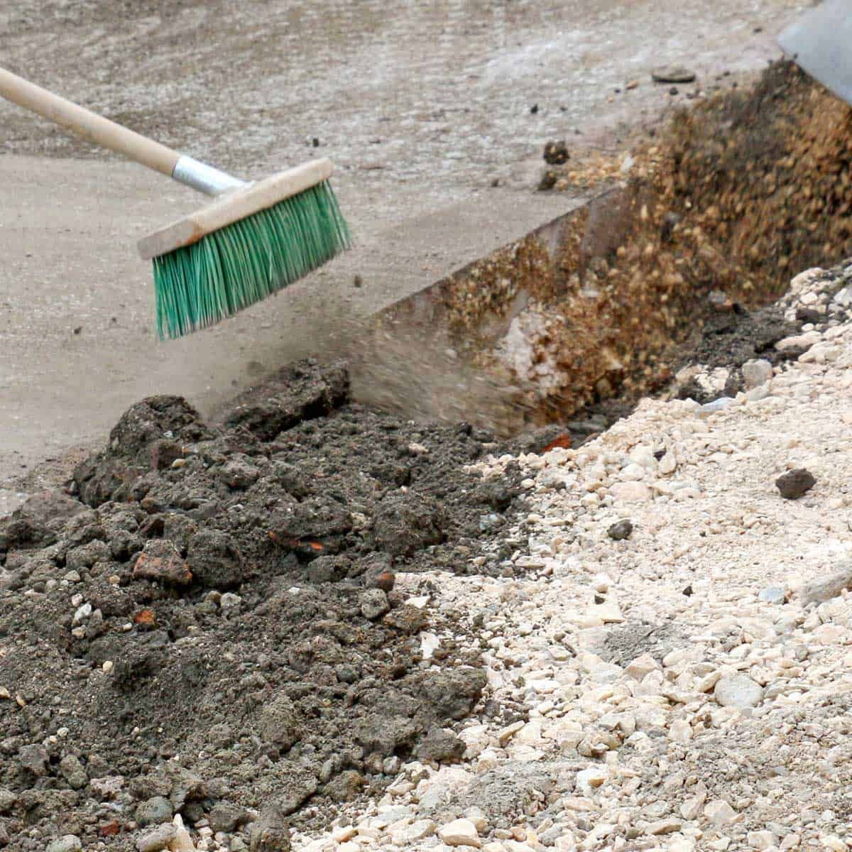A broom sweeps dirt and debris on a construction site.