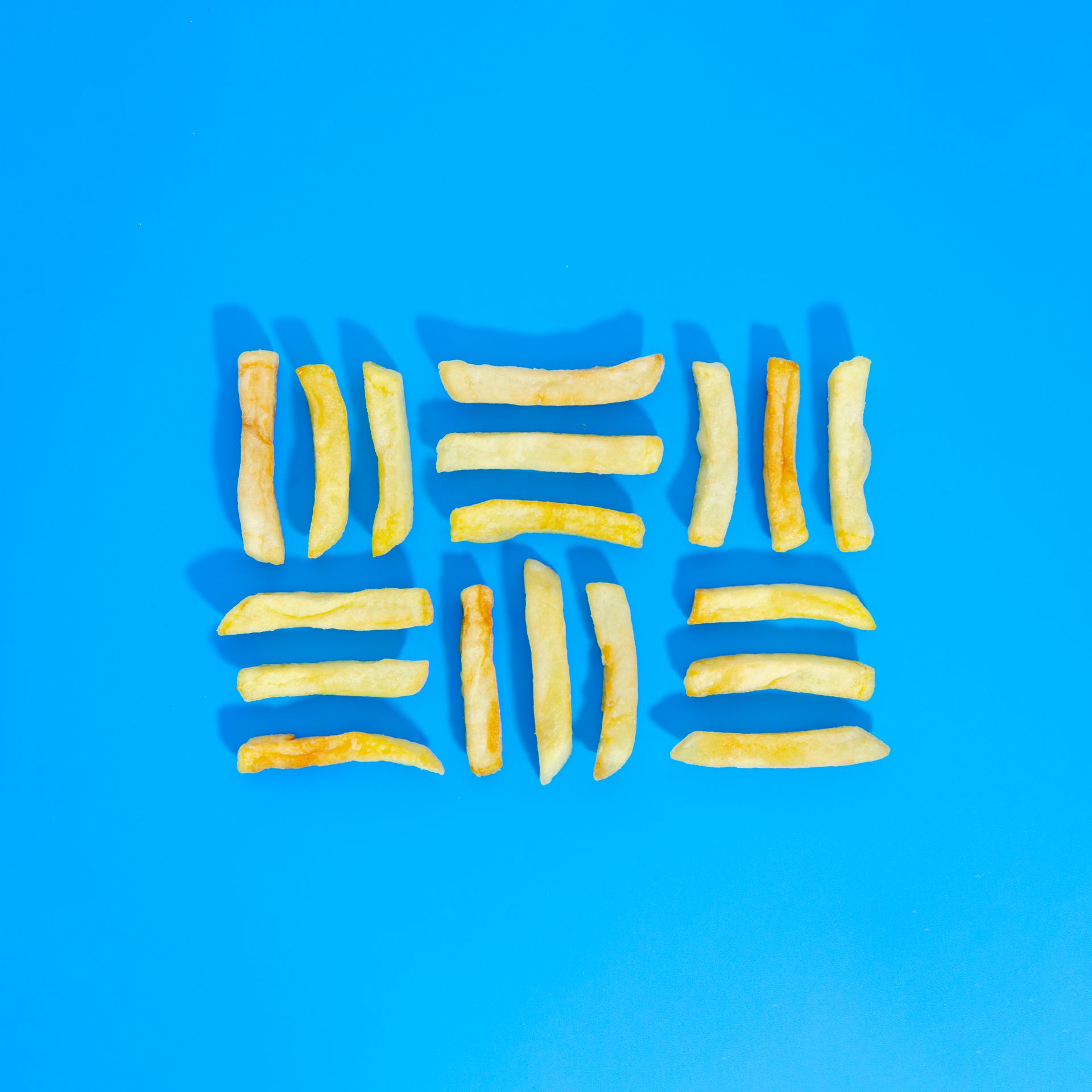 Frites disposées sur un fond bleu, formant un motif en forme de grille.