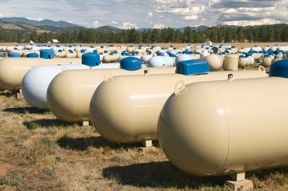 A bunch of propane tanks are lined up in a field