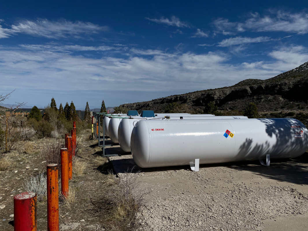 A row of propane tanks are lined up in a field.