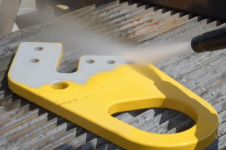 A man wearing a yellow helmet is spraying a blue object