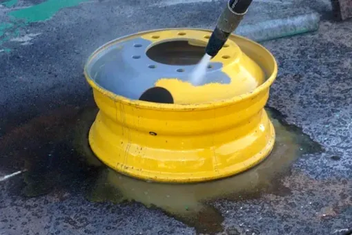 Contact Us A yellow wheel is being cleaned with a high-pressure washer.