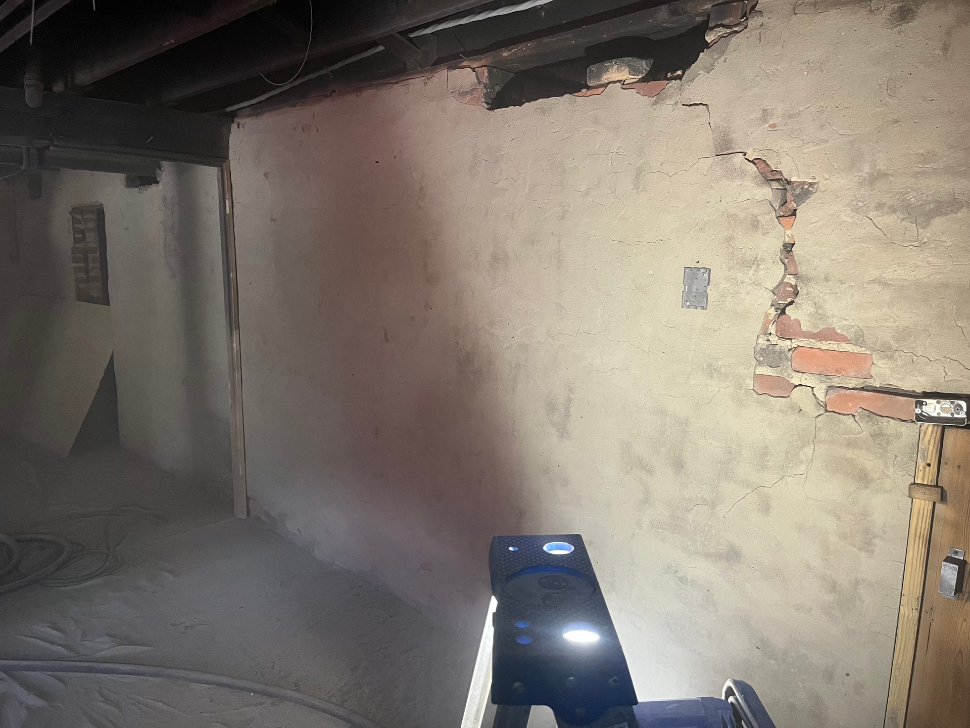 A projector is sitting in a dark room next to a wall.