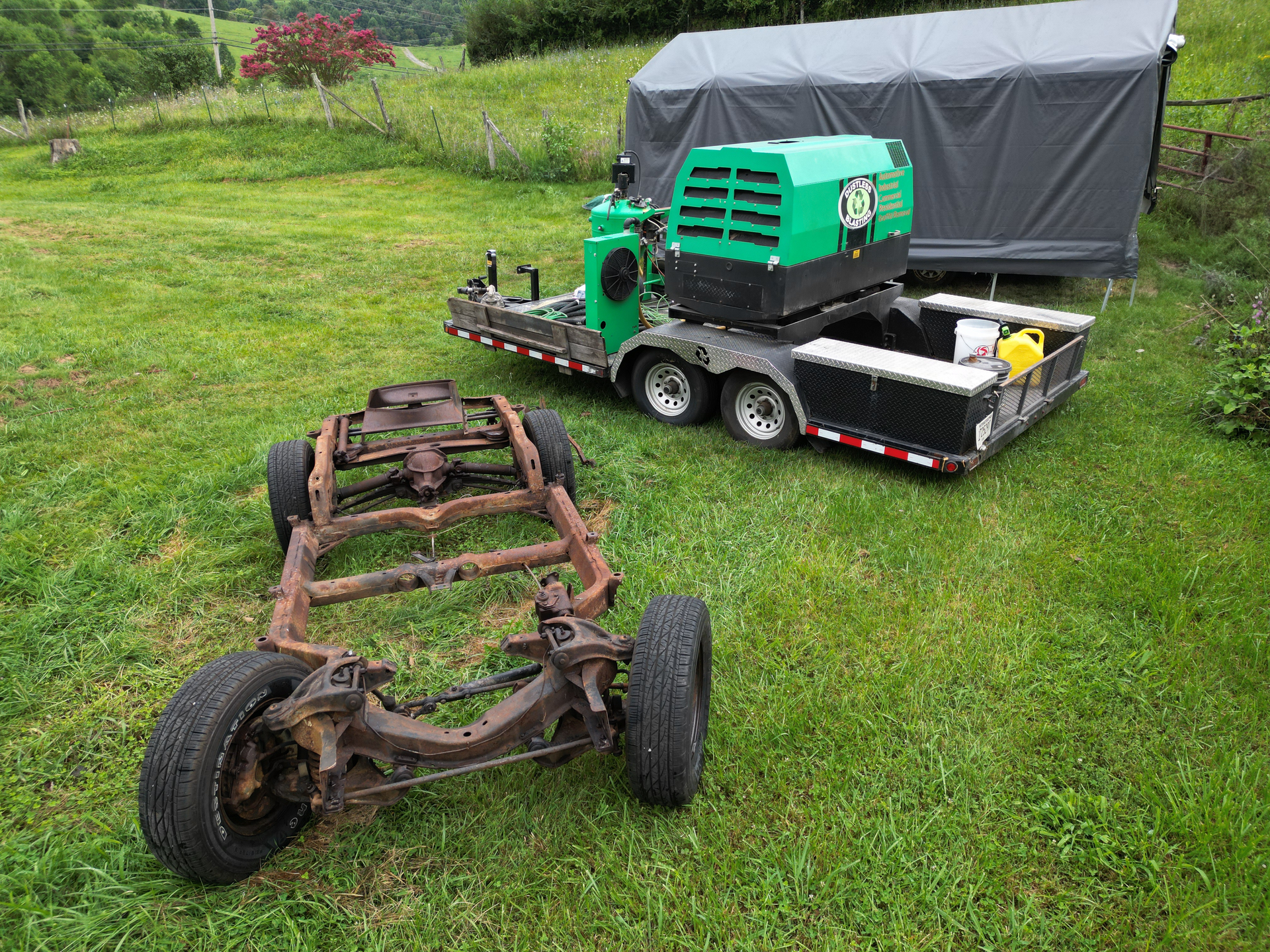 A trailer with a green machine on it is parked in a grassy field.