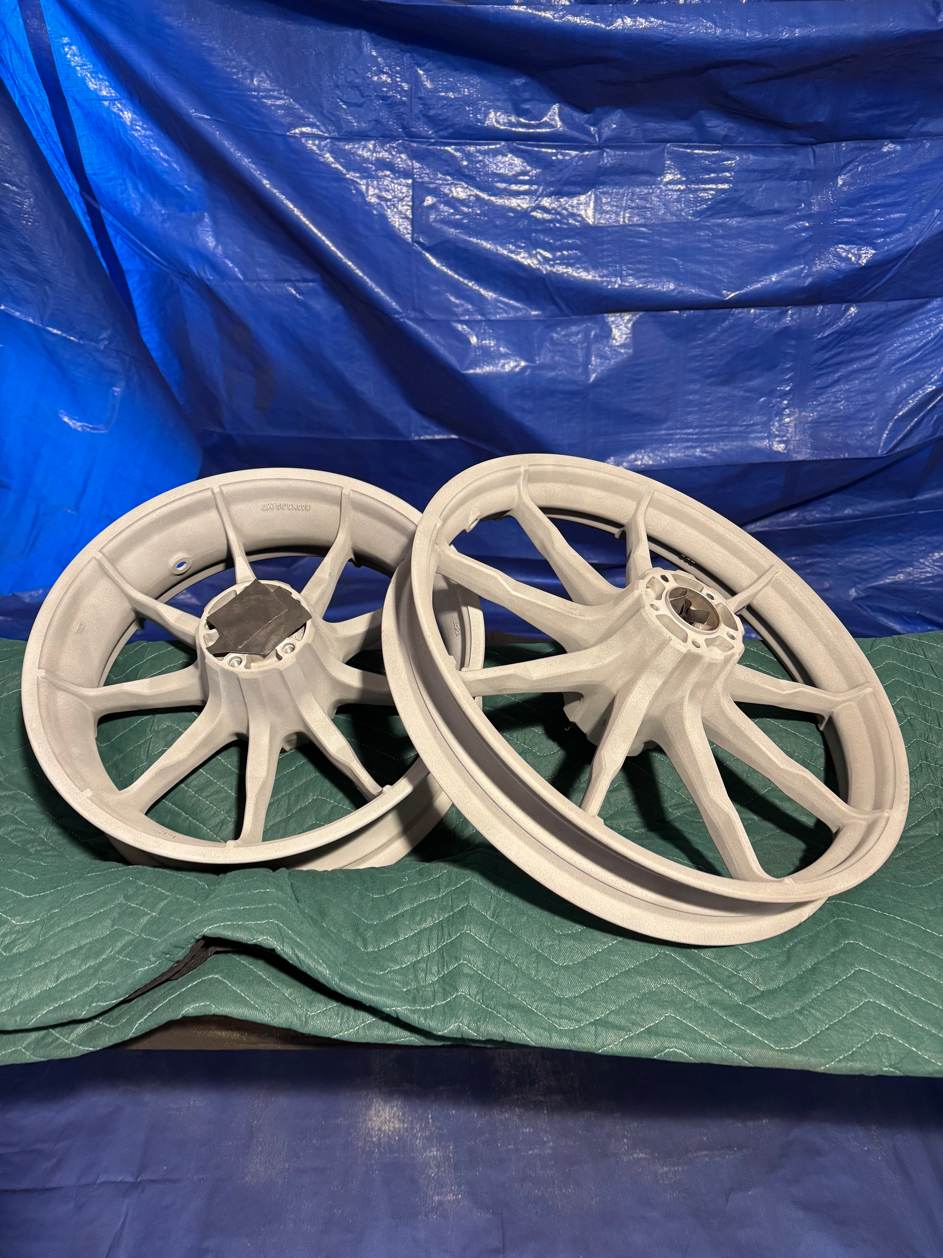 Two white wheels are sitting on a green table in front of a blue tarp.