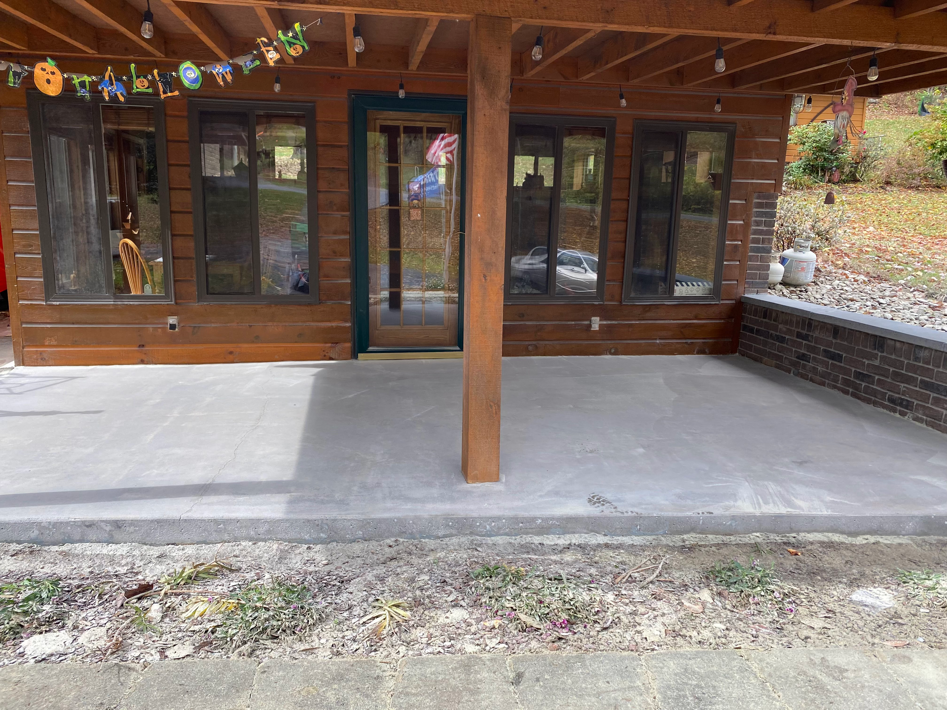 A wooden house with a concrete patio in front of it.