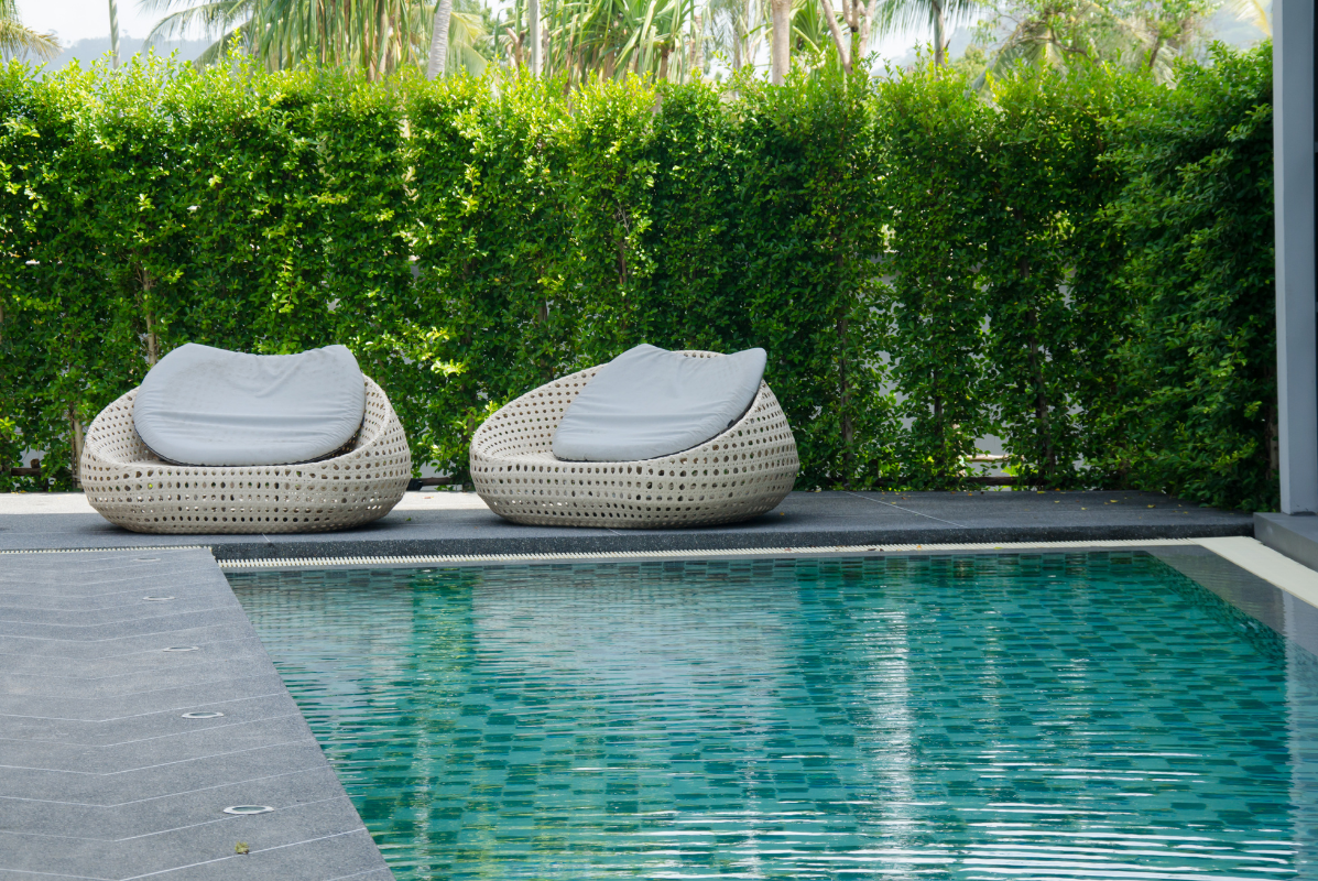 Two chairs are sitting next to a swimming pool.