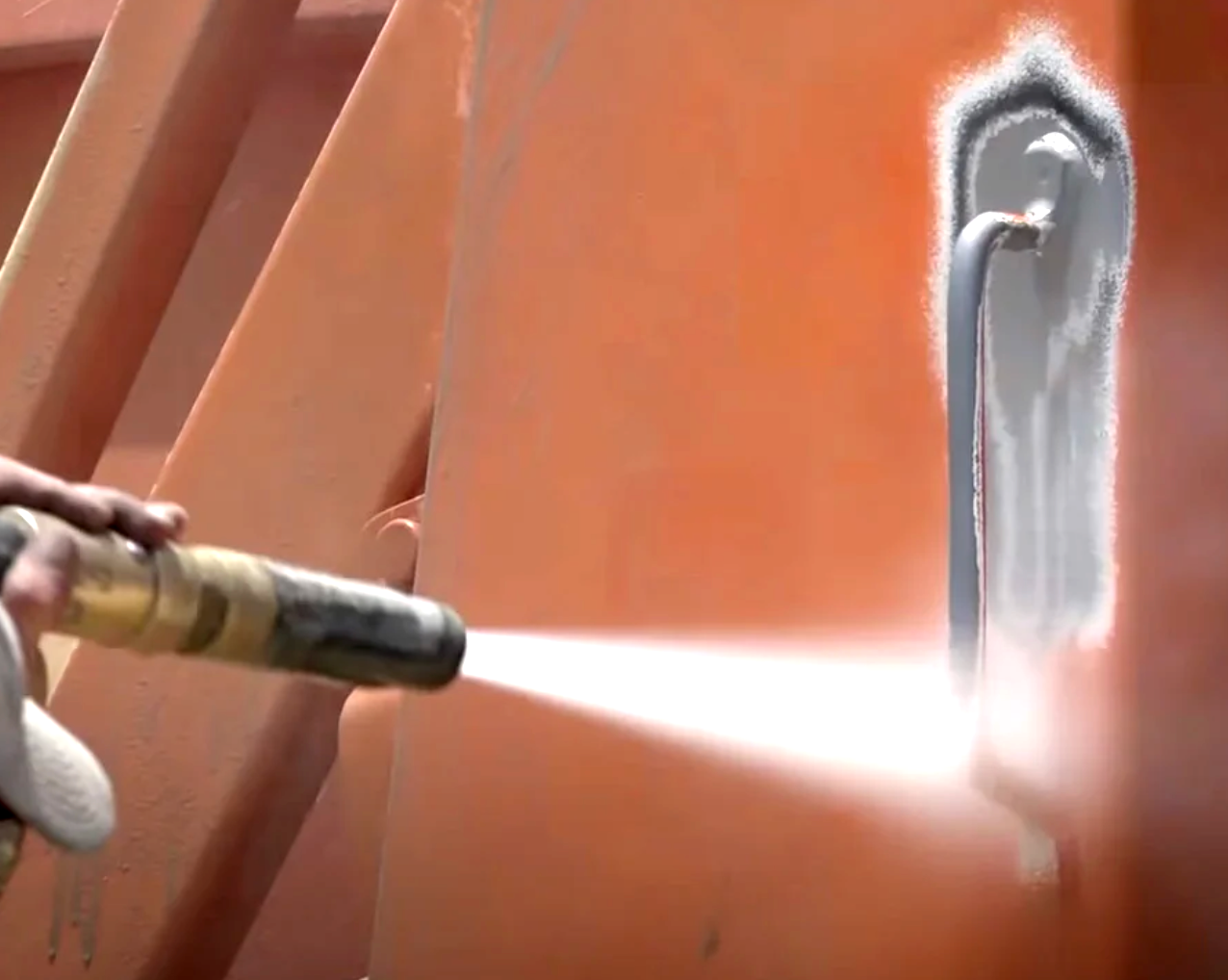 Dusltess sandblasting hose removing paint from a metal sheet
