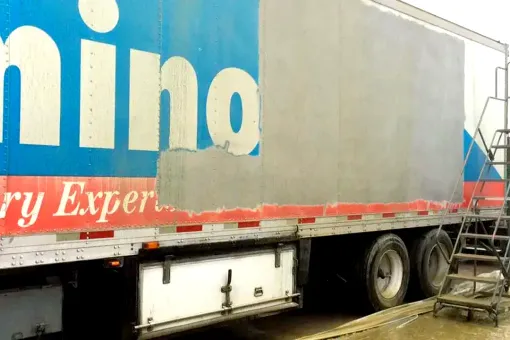 Contact Us A truck with a commercial graphic on the side, halfway stripped off by a sandblaster.