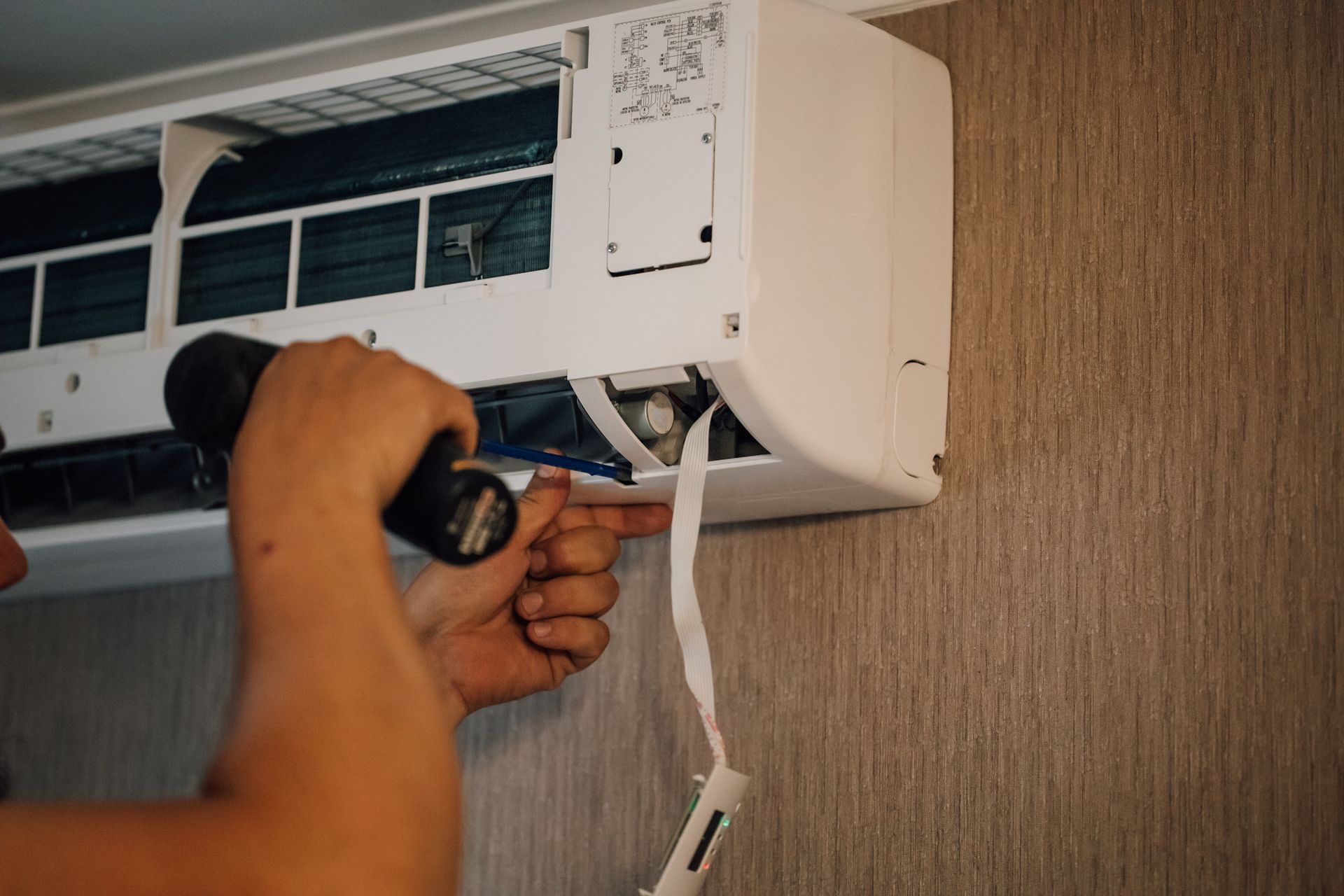 A man is fixing an air conditioner with a drill. A man is fixing an air conditioner with a drill.