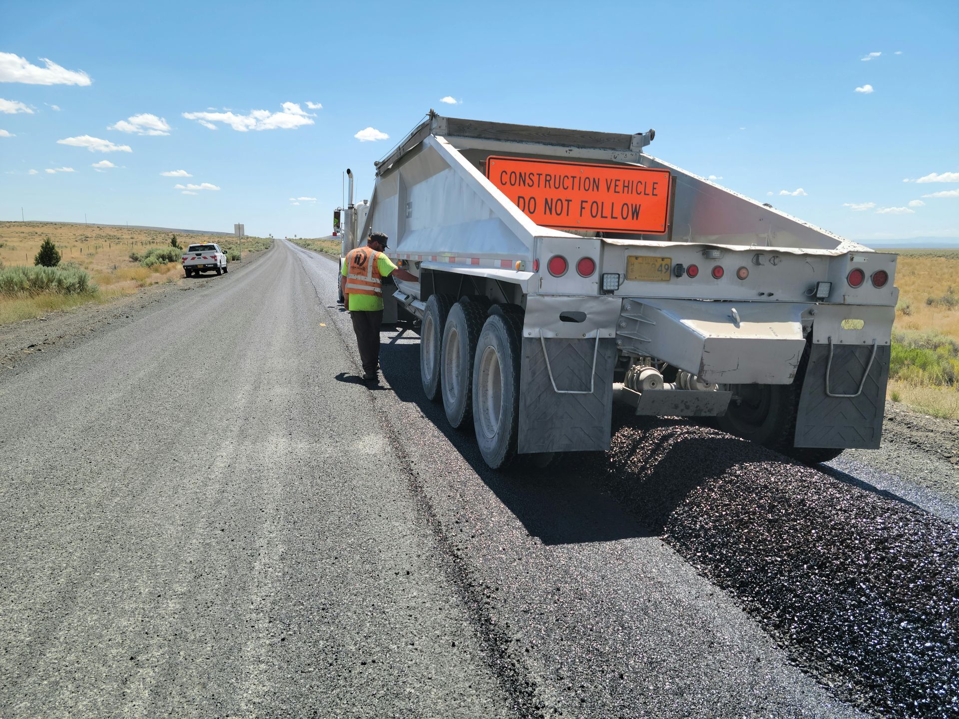 A dump truck has a sign on the back that says