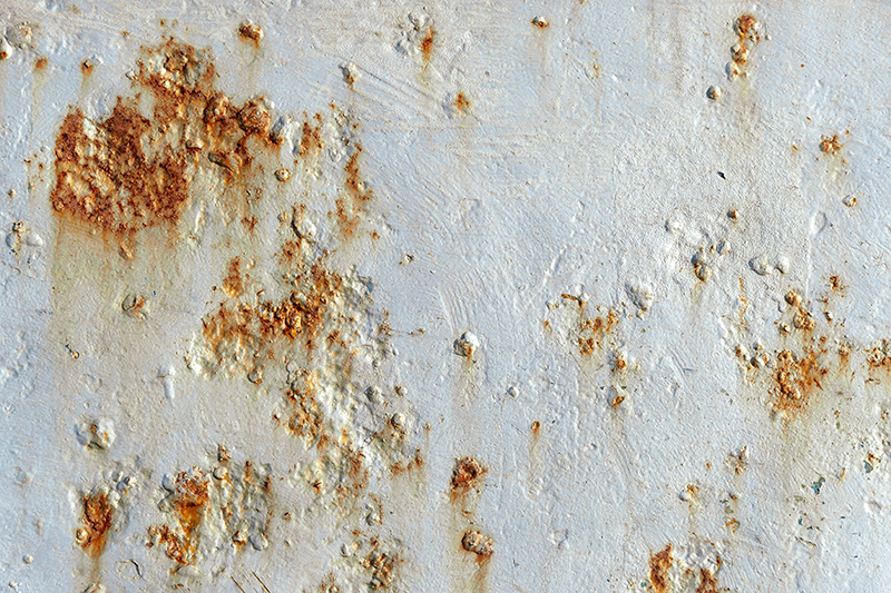 A close up of a rusty metal surface with white paint.