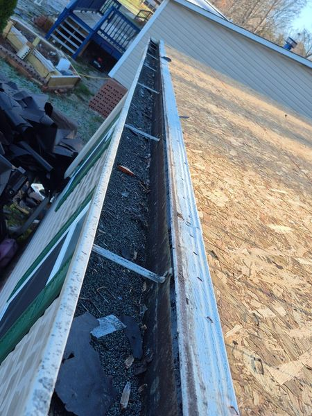 A dirty, debris-filled gutter on the edge of a roof