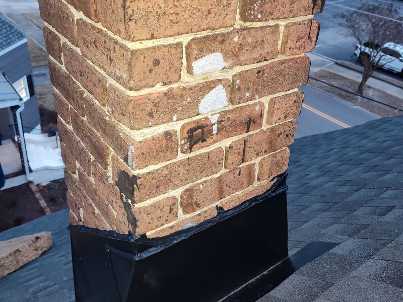 Brick chimney on a dark shingled roof