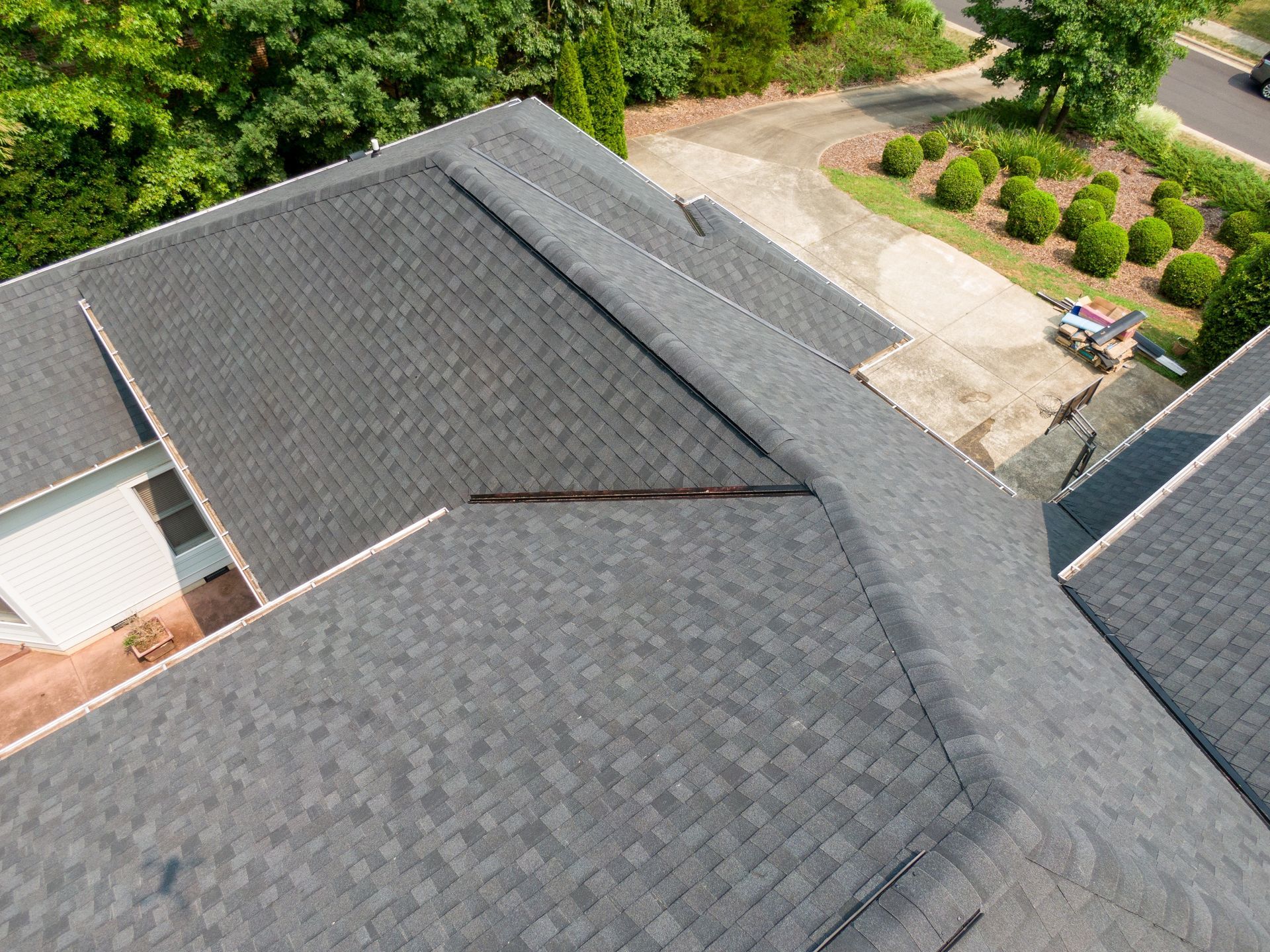 Overhead view of a dark gray asphalt shingle roof with a visible ridge
