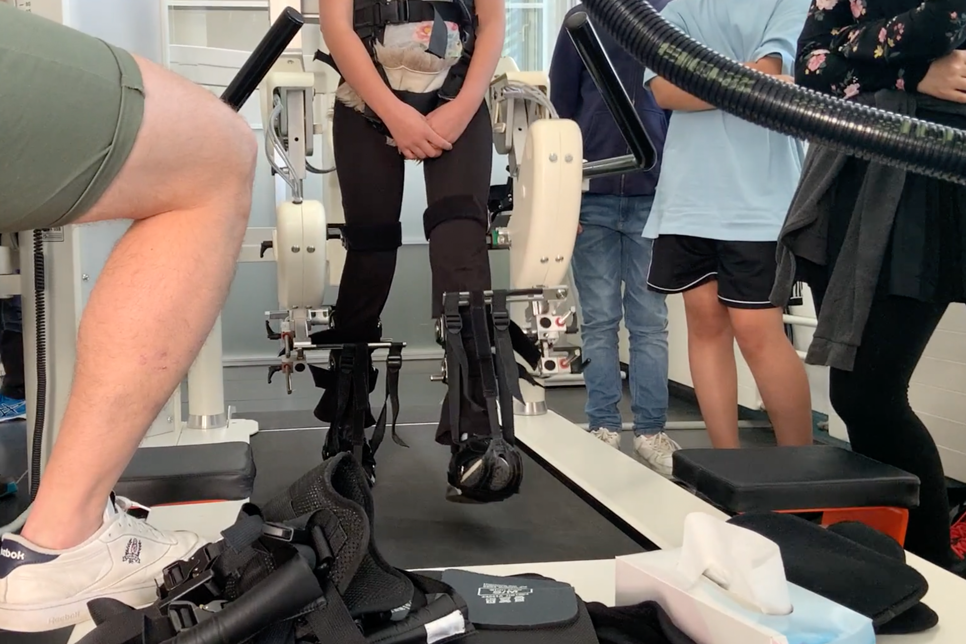 Jugendliche beobachten wie ihre Mitschülerin auf dem HOCOMA-Laufgerät trainiert.