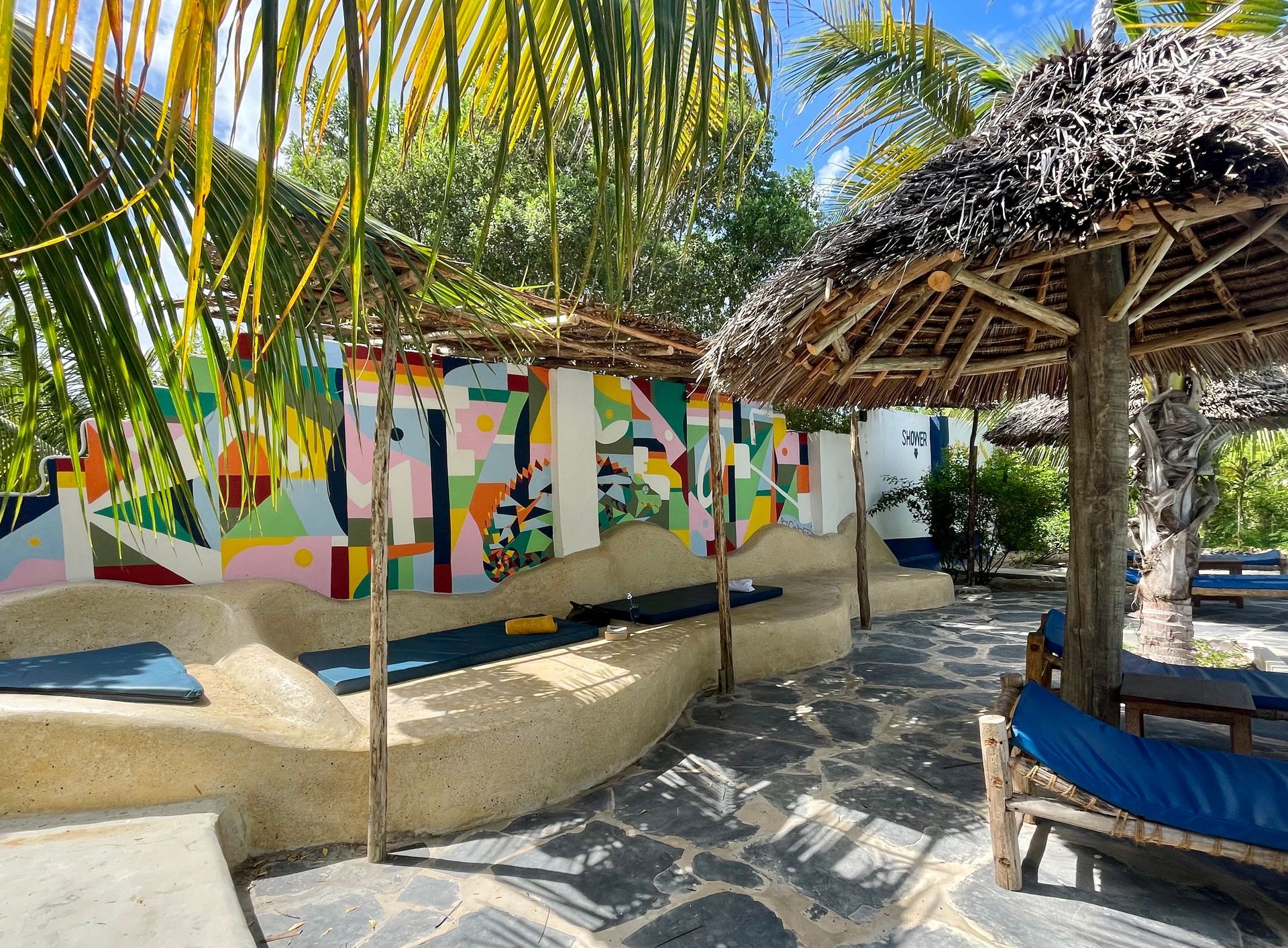 There is a painting on the wall behind the umbrellas.