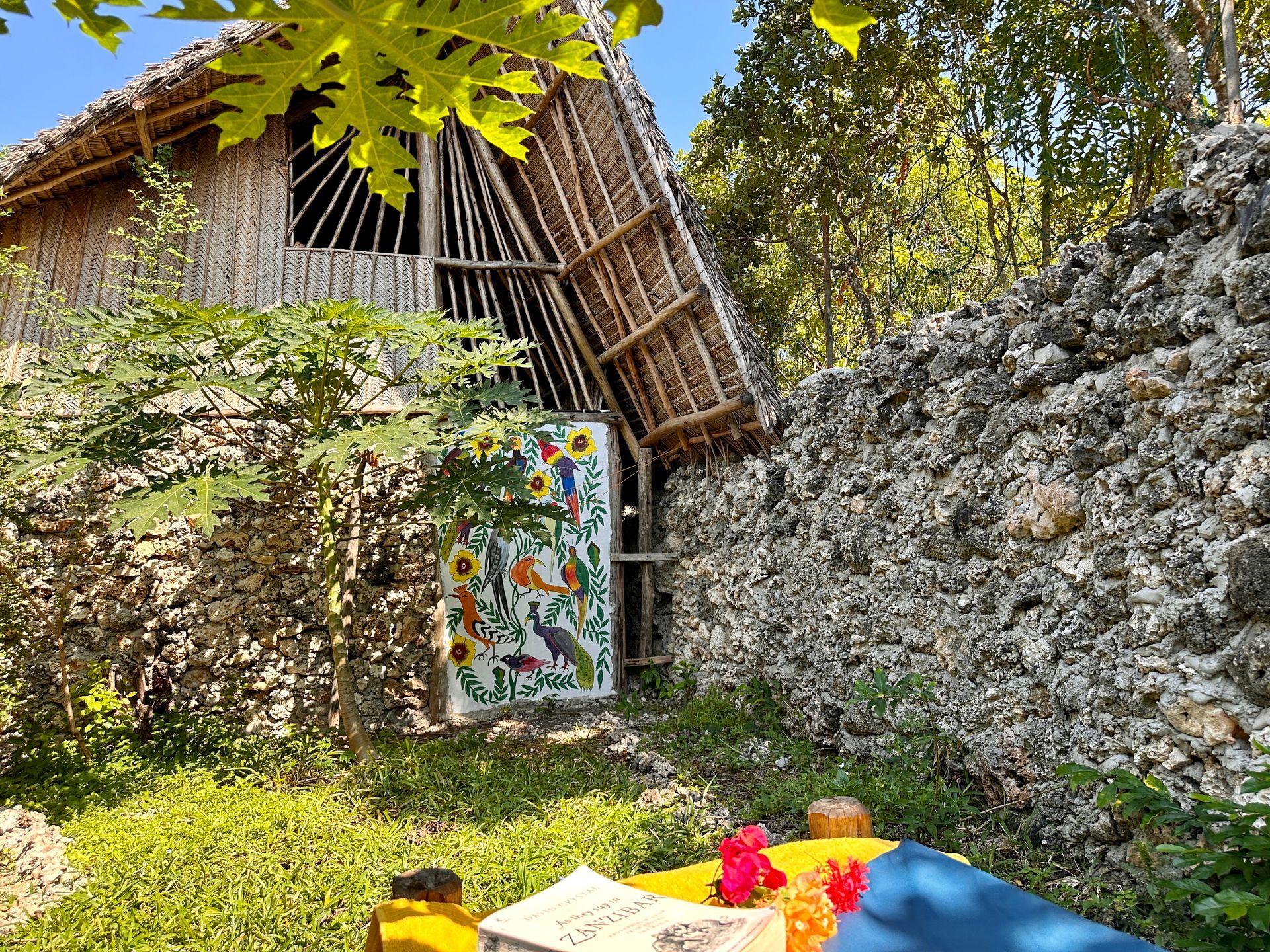 A small hut with a thatched roof is sitting next to a rock wall.