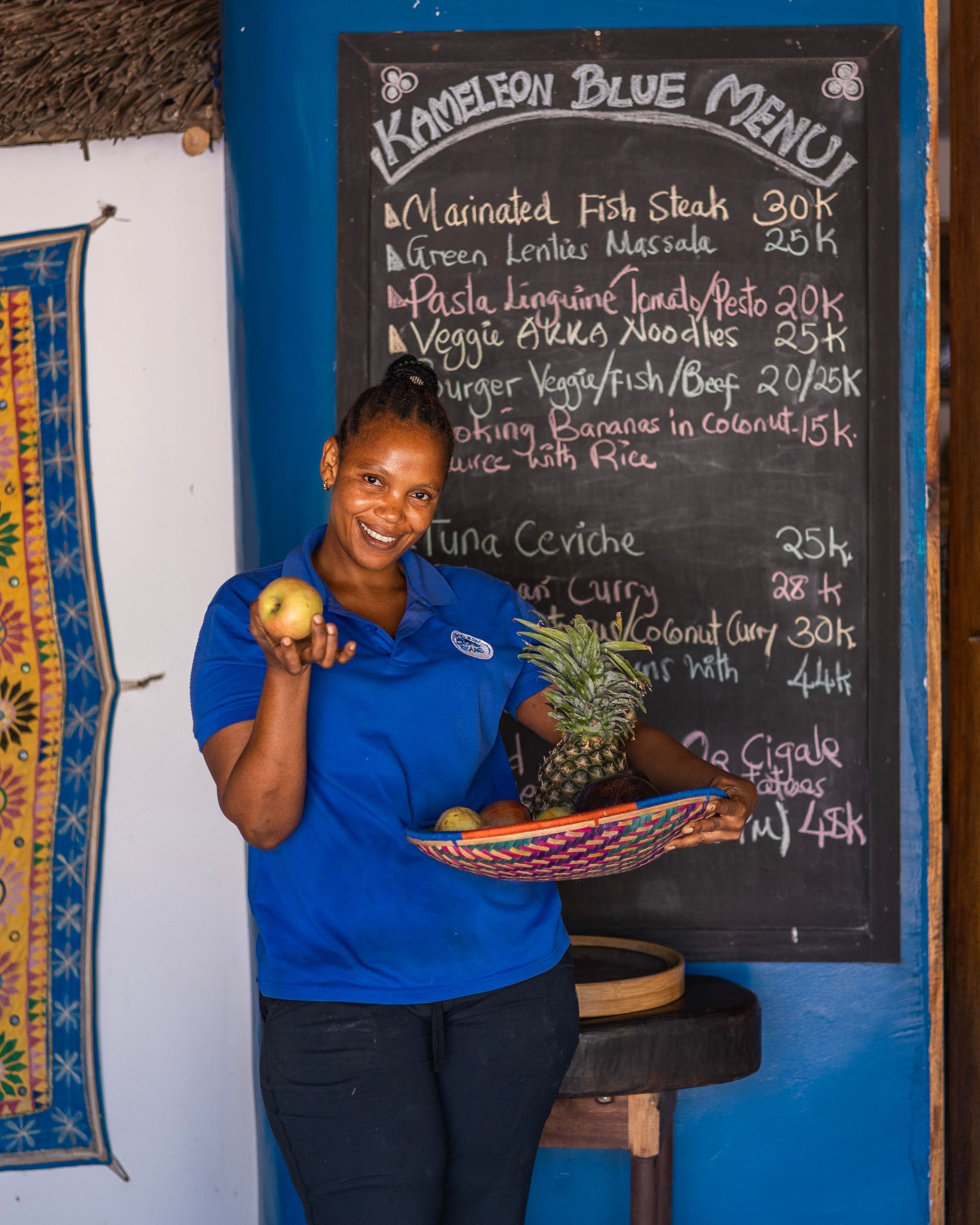 A woman in a blue shirt is standing in front of a menu board