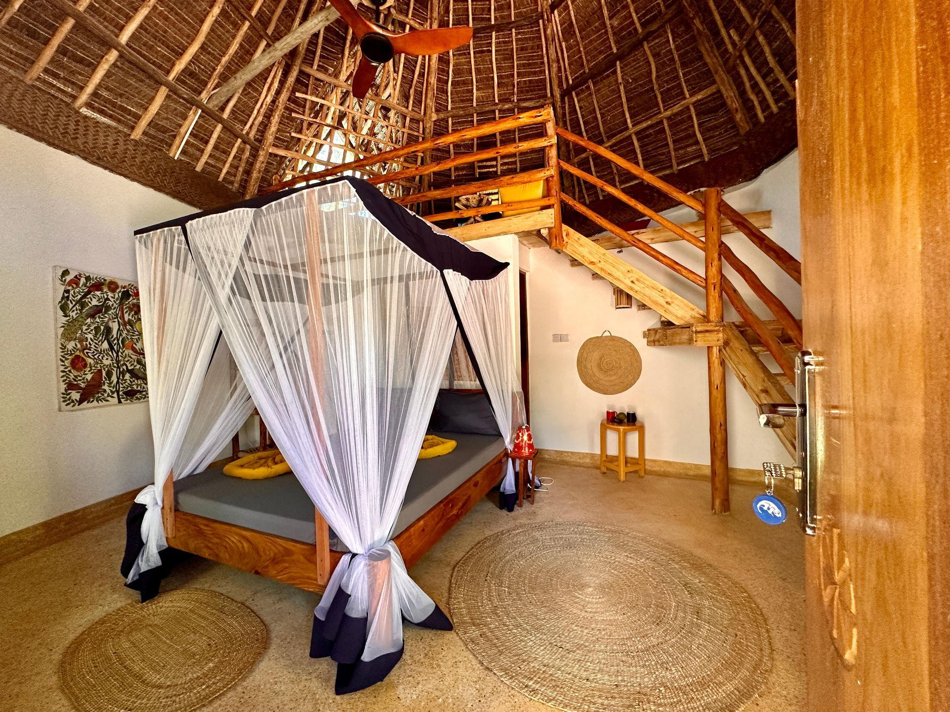 A bedroom with a canopy bed and stairs leading to the second floor.