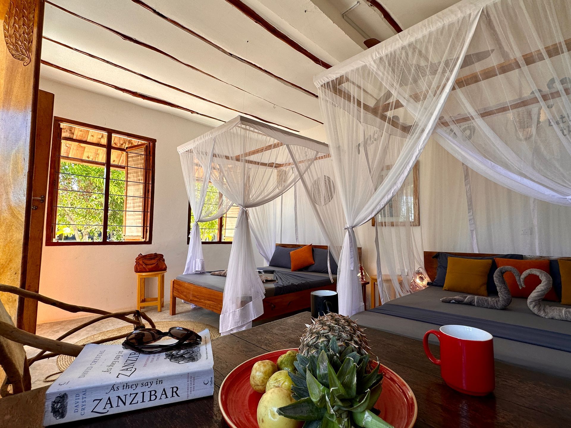 A living room with a canopy bed and a plate of fruit on a table.