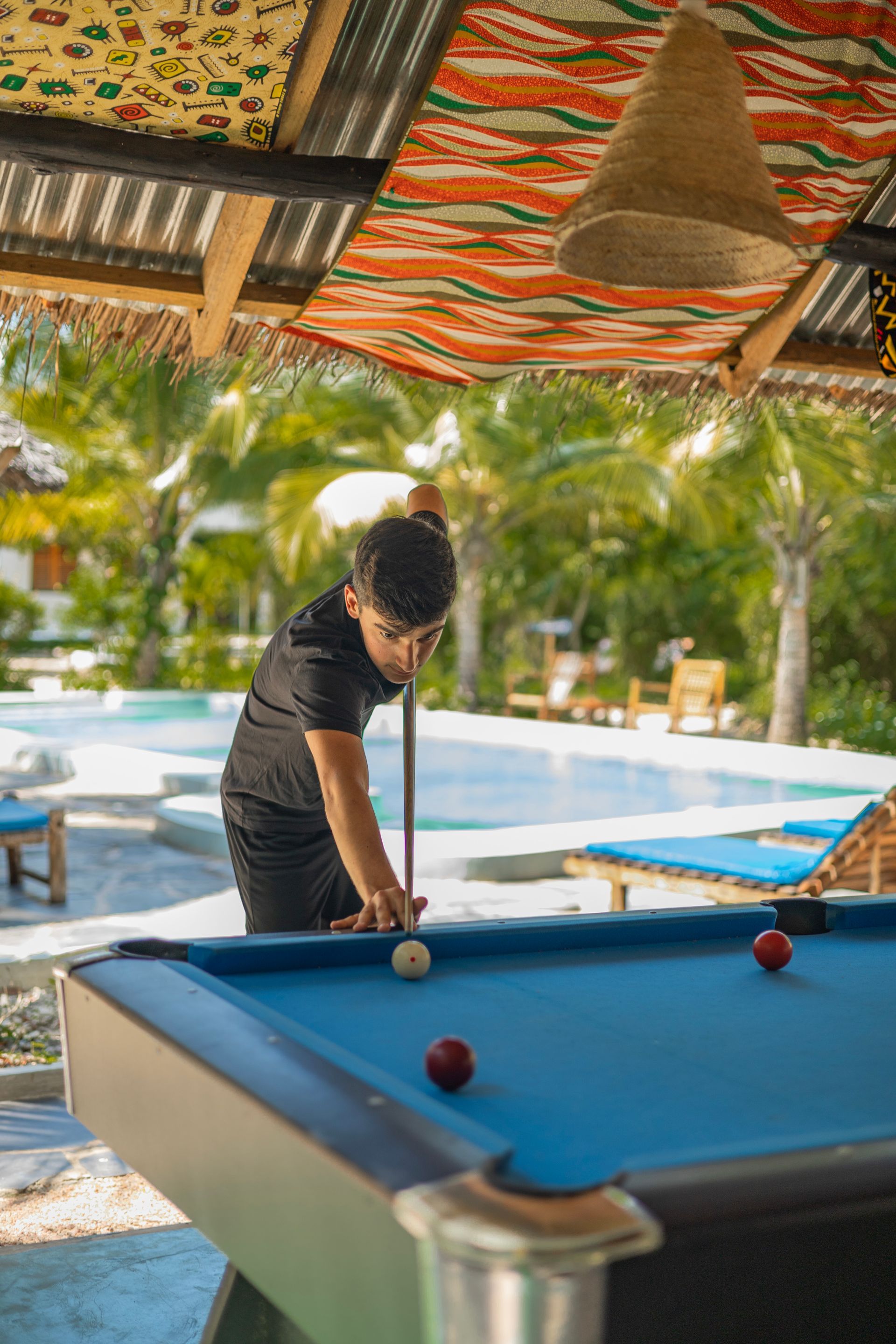 A man is playing pool in front of a pool table.