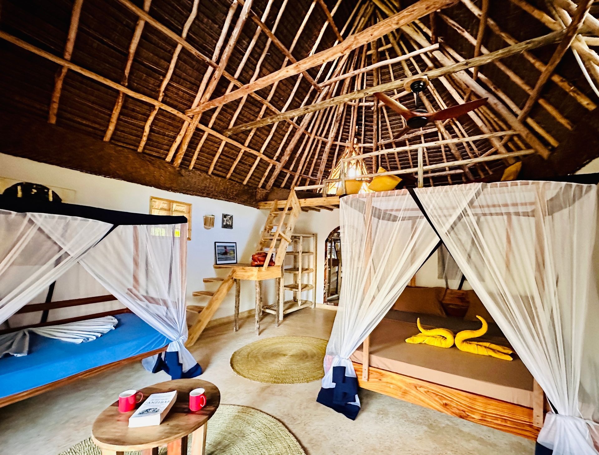 A room with two canopy beds and a table