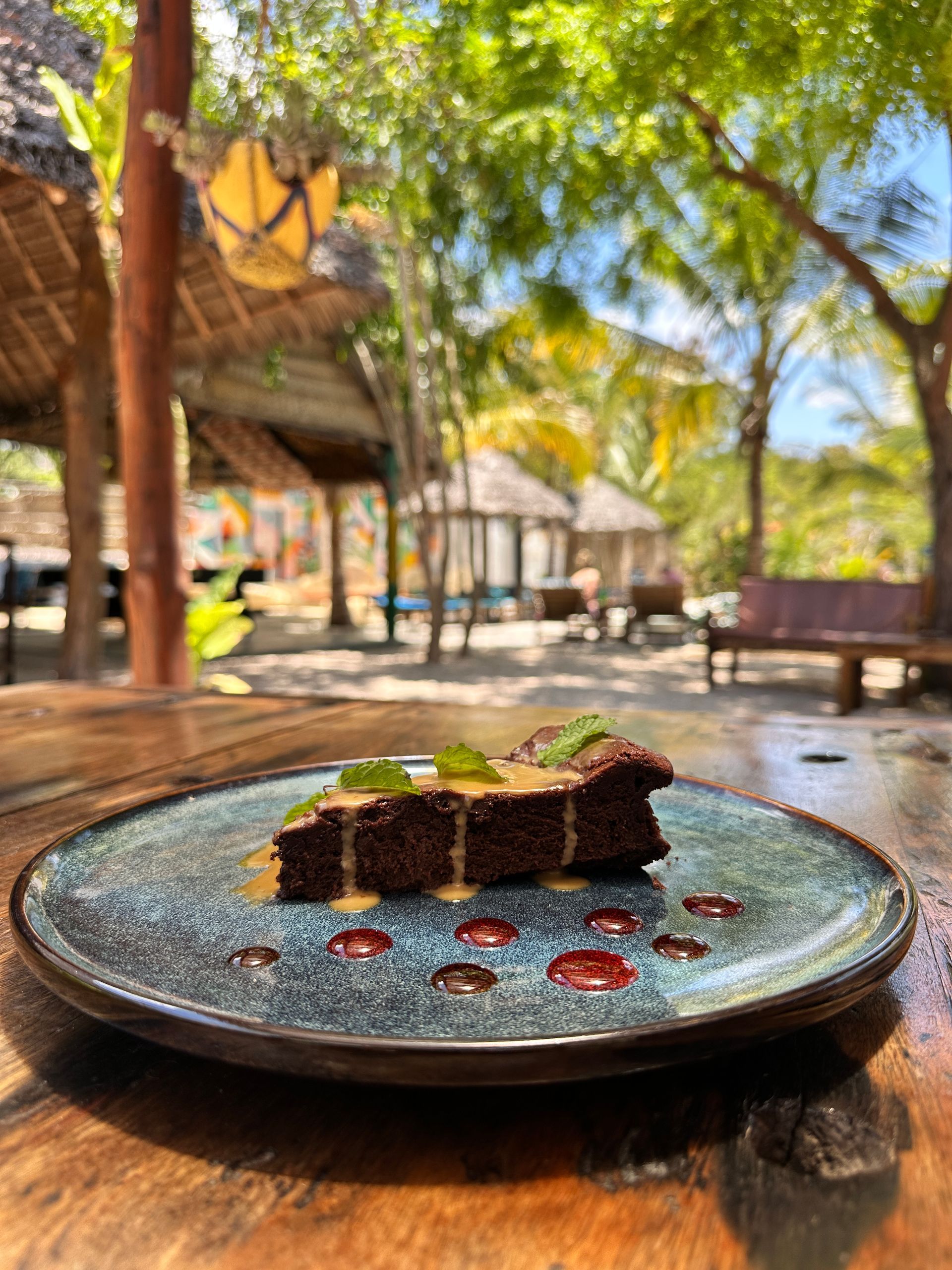 Chocolate dessert on a blue plate outdoors in a tropical resort setting
