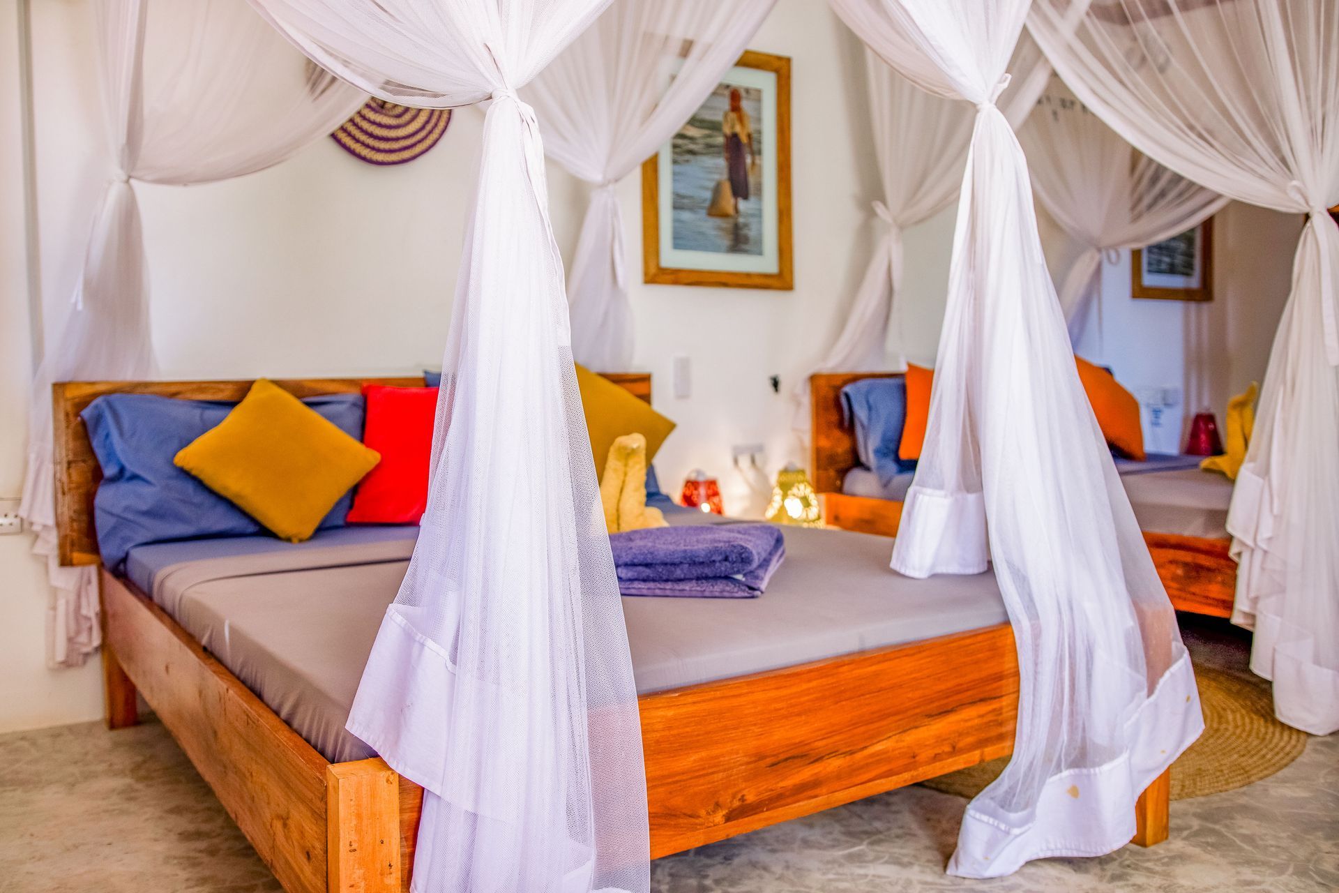 Bedroom with a wooden bed, mosquito net, and colorful pillows.