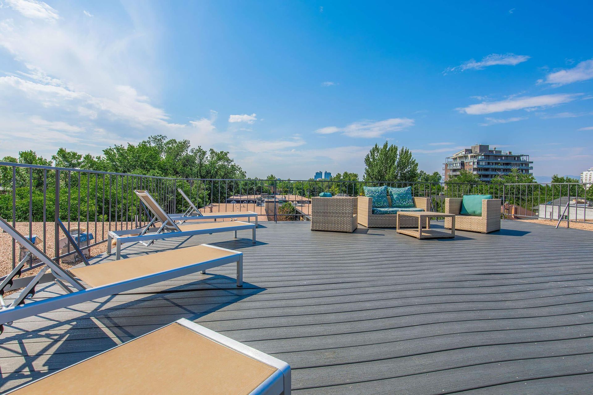 Rooftop patio with lounge chairs and wicker furniture on a sunny day.