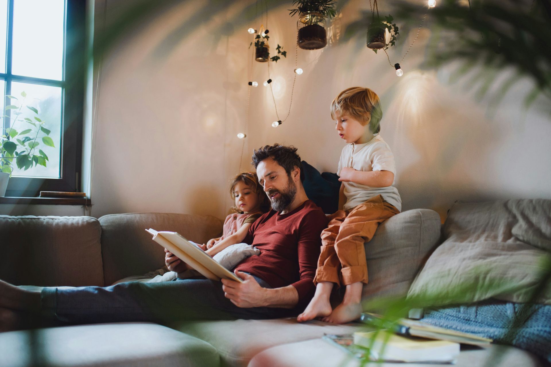 Family sitting on a couch, reading together in a cozy living room with soft lighting.