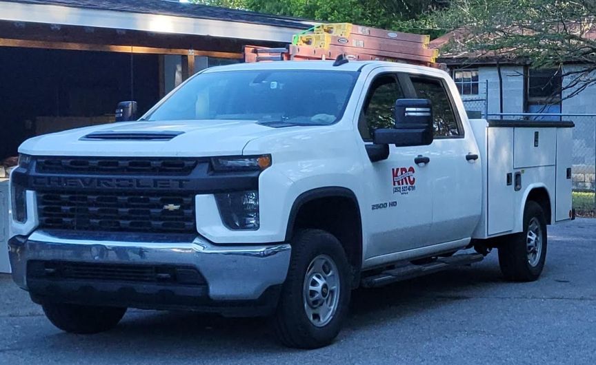 White utility pickup truck parked on a street, side view with company logo on the door
