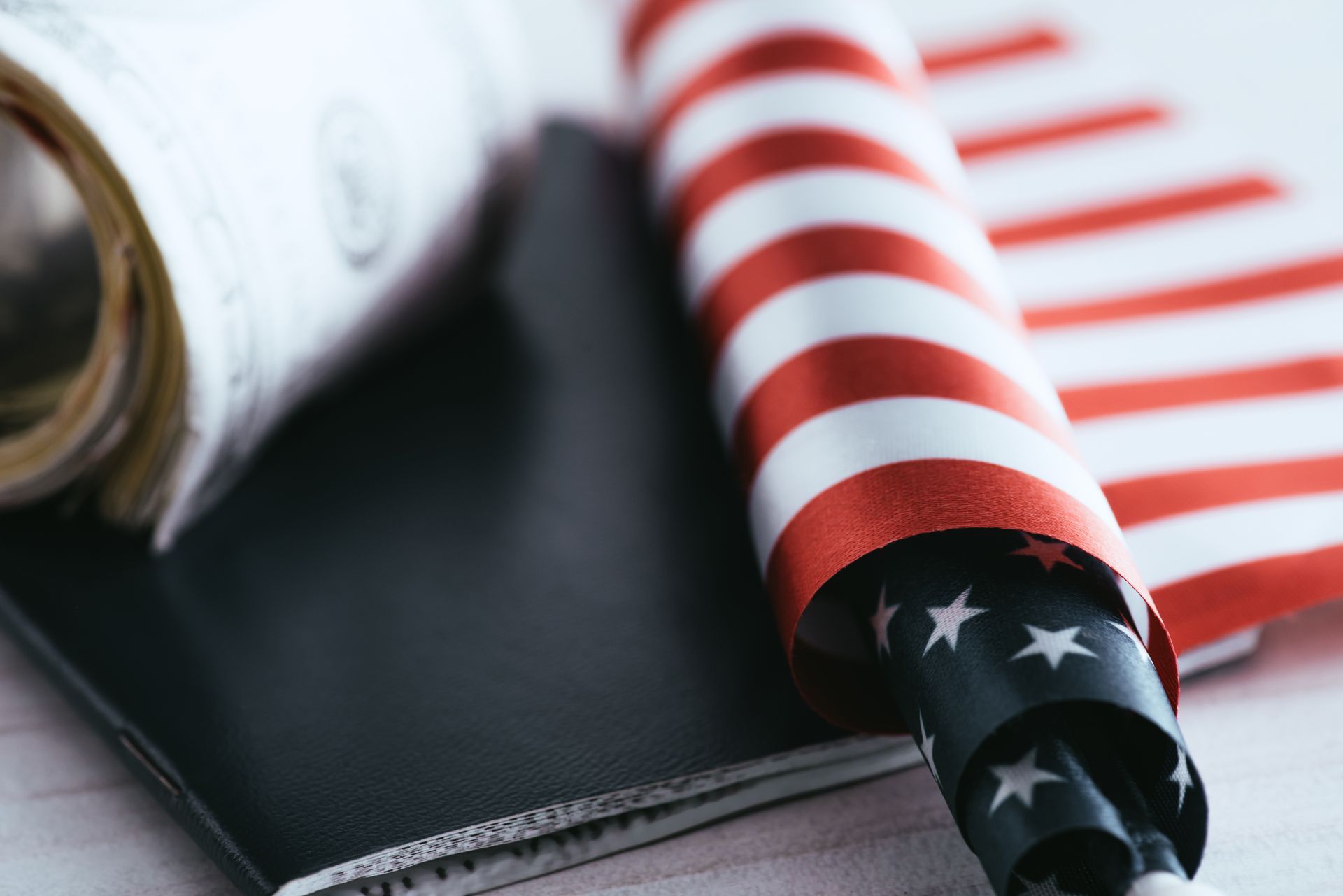 Rolled US flag and money next to a passport, suggesting travel or financial matters.