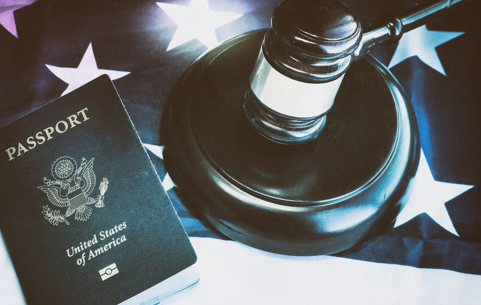 U.S. passport beside a judge’s gavel on a star-spangled flag background