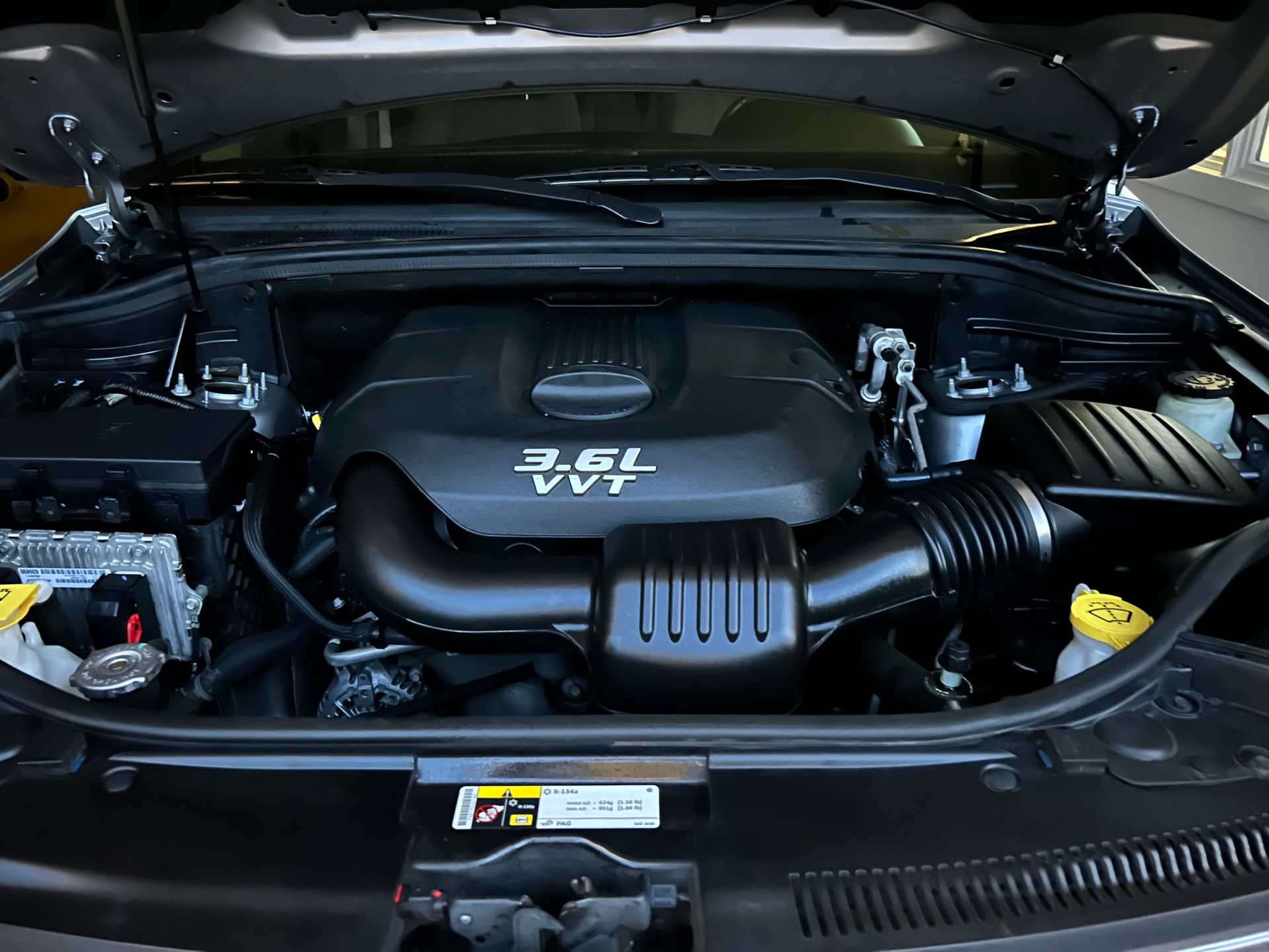 Black car engine bay with a 3.6L VVT engine. Hood open.