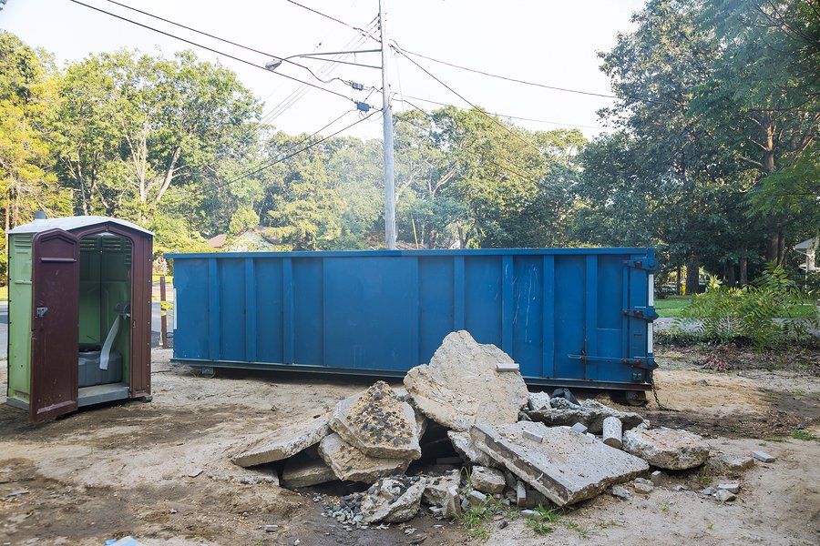 blue dumpster beside the portable comfort room