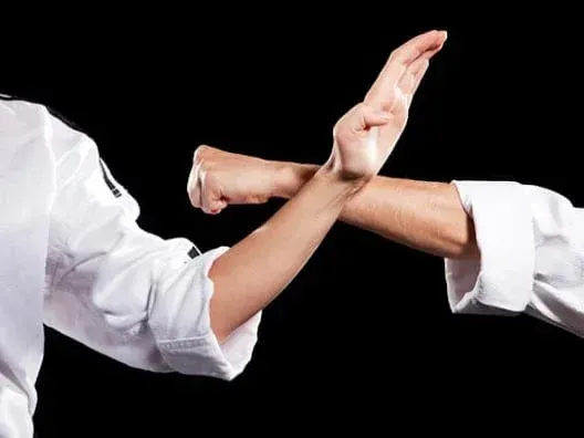 Two hands crossed blocking a jab at a jiu jitsu gym