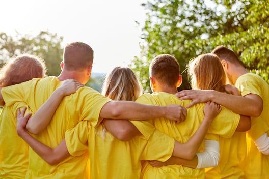 A group of people in yellow shirts are hugging each other.