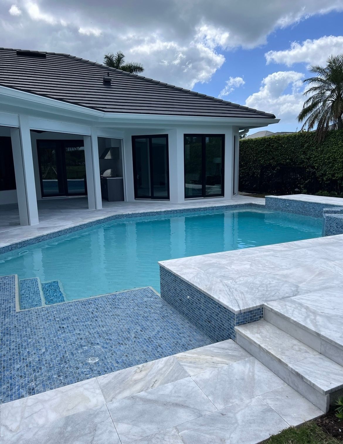 A large swimming pool is in the backyard of a house.