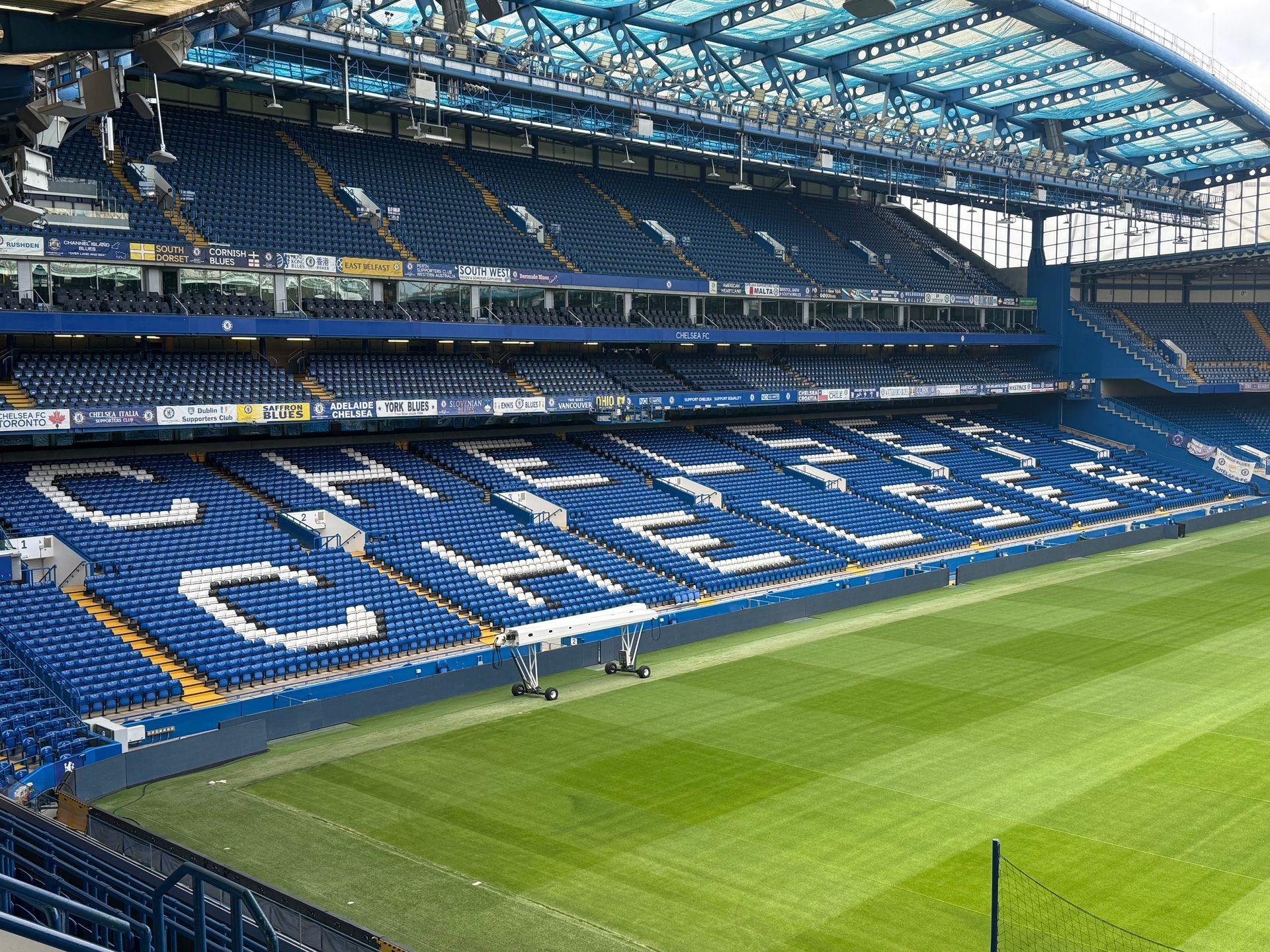 Empty blue Chelsea football stadium with green field. 