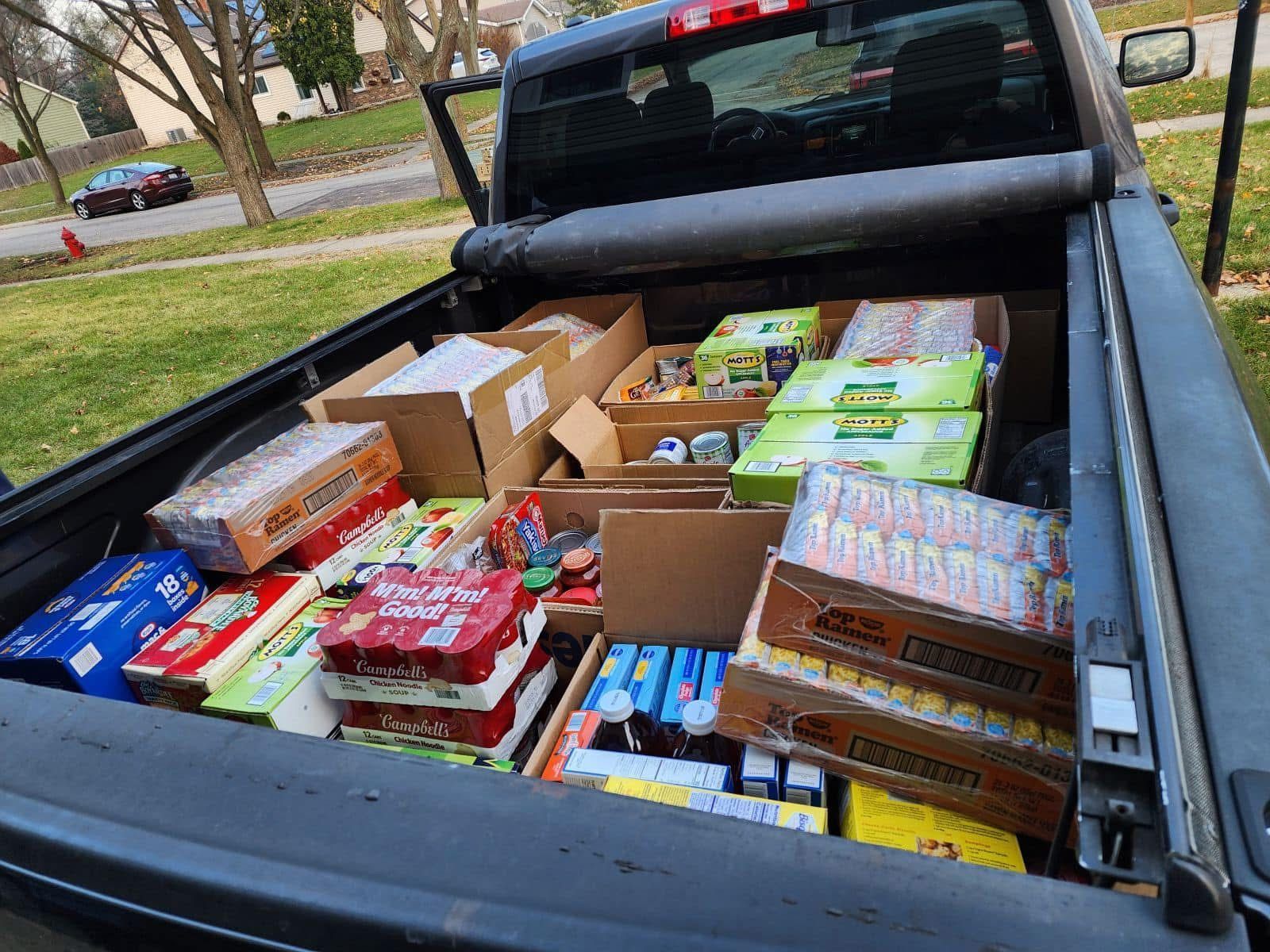 Pickup truck bed filled with boxed food items for donation.