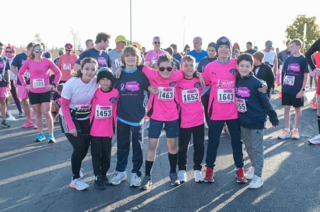 Group of people in pink shirts at a race, posing for a photo.