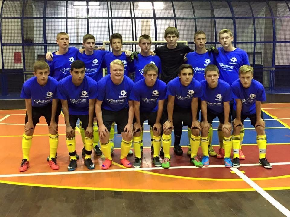 Soccer team in blue jerseys and yellow socks posing on a court.