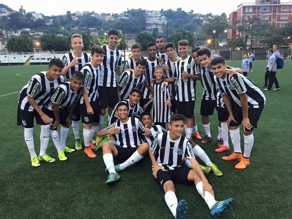 Soccer team in black and white striped jerseys posing on a green field. Players smiling and looking at the camera.