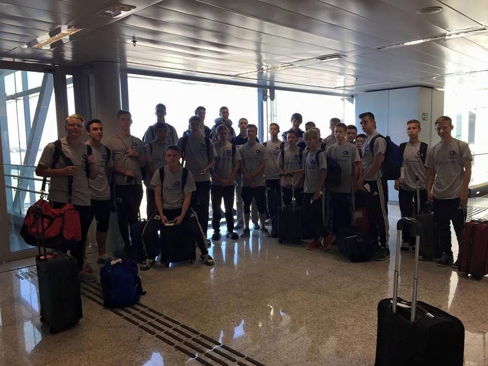 Group of people in matching shirts with luggage at an airport.