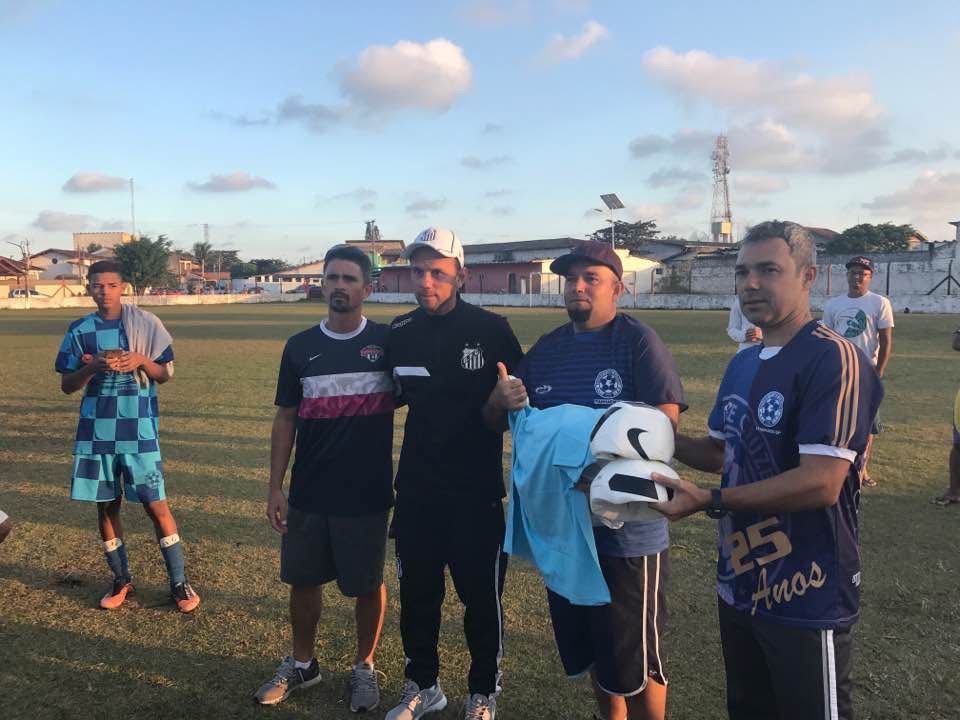 Soccer team on field, men in jerseys, receiving a helmet and shirt, sunny day.