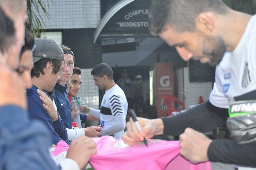 Soccer player signing autographs outside a building with 