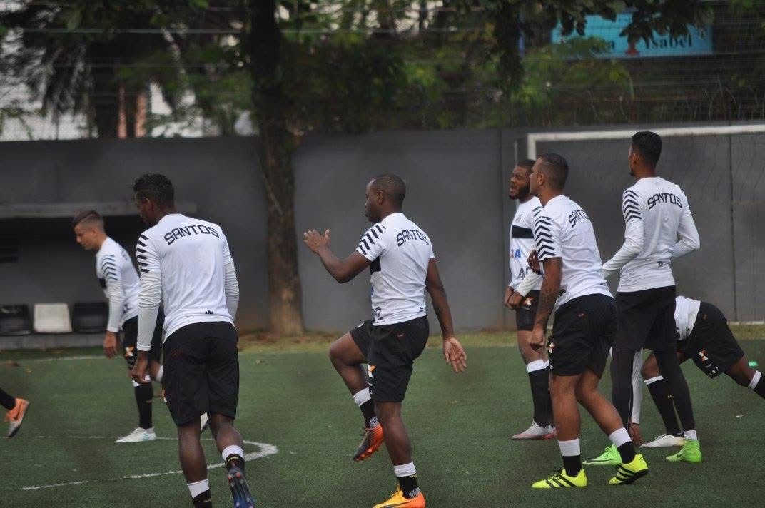 Soccer players in black and white uniforms warming up on a green field.