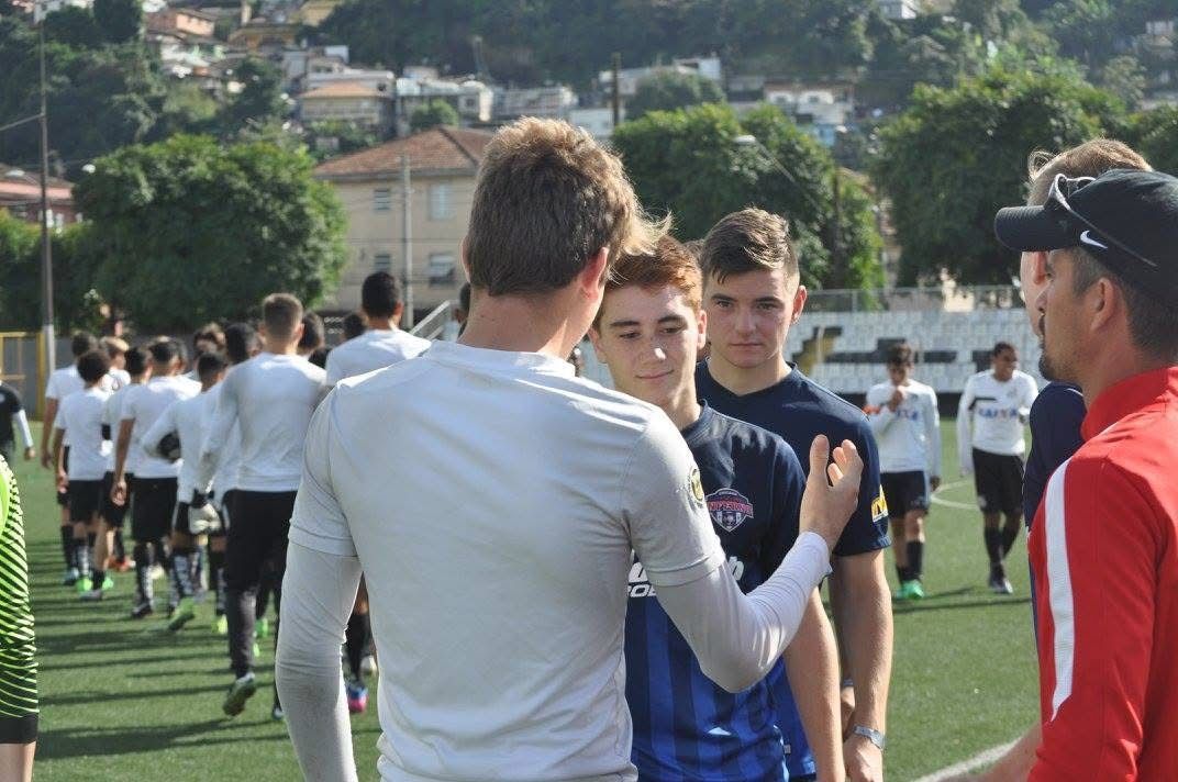 Soccer players in uniform being addressed by coaches on a field.